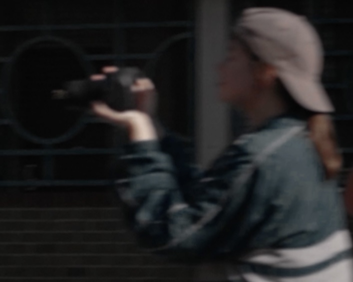 Ana filming in motion, blurred against a dark railing